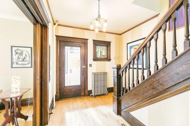 1311 Monroe St NE, Minneapolis, MN 55413 - entrance foyer featuring radiator heating unit, light wood-style flooring, crown molding, stairway, and a chandelier