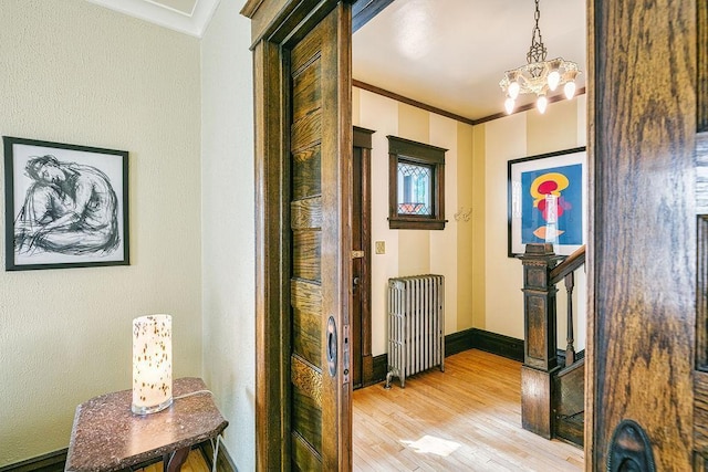 1311 Monroe St NE, Minneapolis, MN 55413 - corridor featuring radiator heating unit, ornamental molding, light wood-style flooring, a chandelier, and baseboards