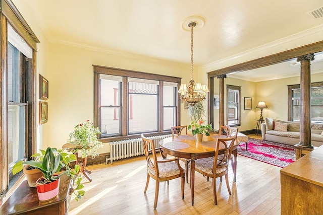 1311 Monroe St NE, Minneapolis, MN 55413 - dining space with radiator heating unit, ornamental molding, light wood finished floors, baseboards, and a chandelier