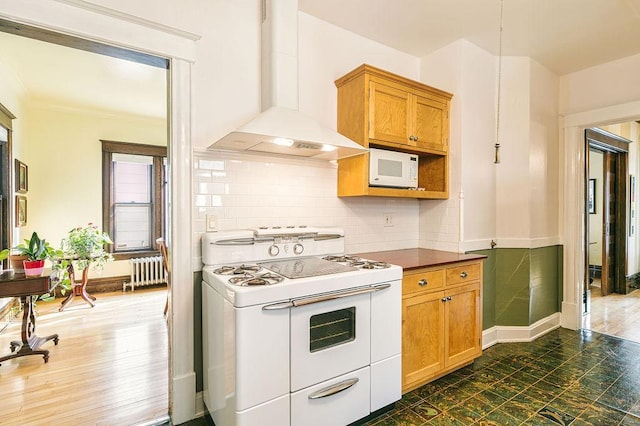 1311 Monroe St NE, Minneapolis, MN 55413 - kitchen with white appliances, wall chimney exhaust hood, radiator, dark countertops, and tasteful backsplash
