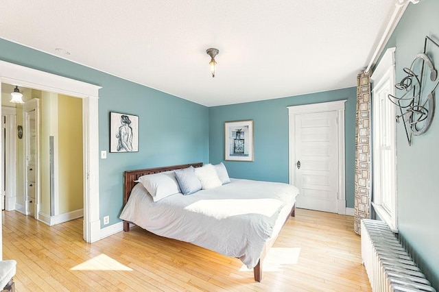 1311 Monroe St NE, Minneapolis, MN 55413 - bedroom with radiator heating unit, light wood-style floors, and baseboards