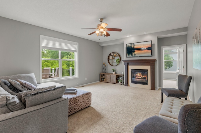 8607 Portage Ln E, Shakopee, MN 55379 - carpeted living room featuring a glass covered fireplace, a ceiling fan, healthy amount of natural light, and baseboards
