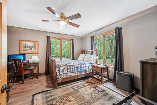 9590 Woodhill Blvd, New Market Twp, MN 55044 - bedroom with multiple windows, light wood-style flooring, a desk, and ceiling fan