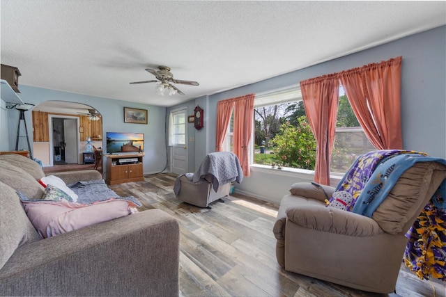 1034 8th St NW, Faribault, MN 55021 - living room featuring a ceiling fan, a textured ceiling, arched walkways, wood finished floors, and baseboards