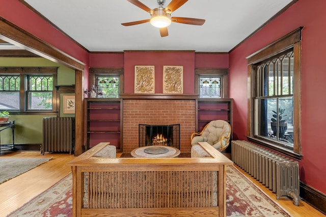 2441 Grand Ave S, Minneapolis, MN 55405 - living room featuring radiator, ceiling fan, wood finished floors, a brick fireplace, and ornamental molding