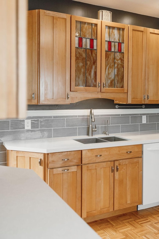 2441 Grand Ave S, Minneapolis, MN 55405 - kitchen featuring a sink, white dishwasher, light countertops, glass insert cabinets, and backsplash