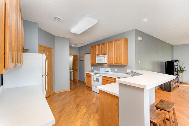 13049 Europa Trail Way N Unit H, Hugo, MN 55038 - kitchen with white appliances, a peninsula, a breakfast bar area, light countertops, and light wood finished floors