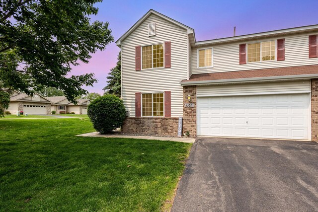 13049 Europa Trail Way N Unit H, Hugo, MN 55038 - traditional-style house with asphalt driveway, brick siding, a lawn, and an attached garage