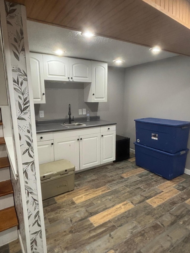 613 13th St SW, Willmar, MN 56201 - kitchen with a sink, dark countertops, dark wood-style flooring, white cabinetry, and recessed lighting