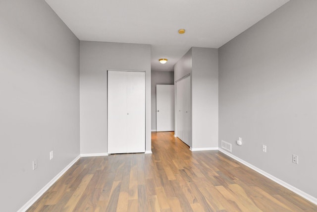 560 2nd St Unit 302, Minneapolis, MN 55401 - unfurnished bedroom featuring baseboards, wood finished floors, and two closets