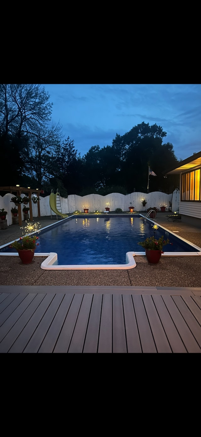 4910 Upper 148th Ct, Apple Valley, MN 55124 - pool at dusk with a water slide, a fenced backyard, and a wooden deck