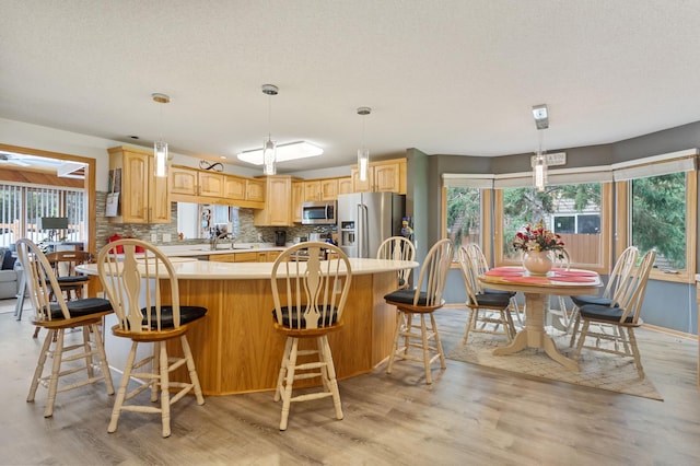 4910 Upper 148th Ct, Apple Valley, MN 55124 - kitchen with stainless steel appliances, light countertops, light wood finished floors, tasteful backsplash, and light brown cabinets