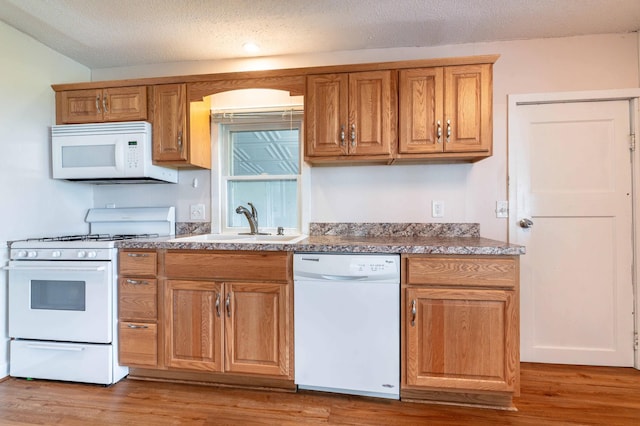 27326 Cloverleaf Ln, Everts Twp, MN 56515 - kitchen featuring white appliances, light wood-style flooring, a sink, brown cabinetry, and a textured ceiling