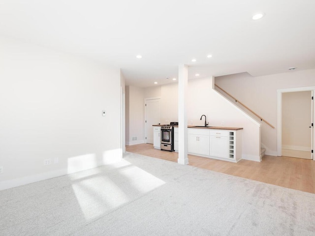 7010 Oak Ridge Rd, Corcoran, MN 55340 - unfurnished living room featuring a sink, light carpet, recessed lighting, stairway, and baseboards