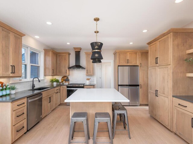 7010 Oak Ridge Rd, Corcoran, MN 55340 - kitchen with appliances with stainless steel finishes, wall chimney range hood, a sink, light wood finished floors, and recessed lighting