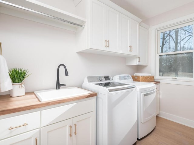 7010 Oak Ridge Rd, Corcoran, MN 55340 - laundry area featuring cabinet space, washer and clothes dryer, light wood-type flooring, and baseboards