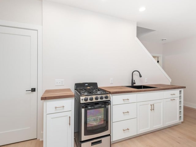 7010 Oak Ridge Rd, Corcoran, MN 55340 - kitchen with wooden counters, stainless steel range with gas stovetop, a sink, light wood-style floors, and white cabinetry