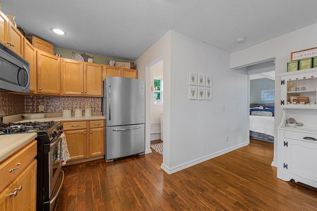 310 Belle St W, Cannon Falls, MN 55009 - kitchen with appliances with stainless steel finishes, light countertops, dark wood-type flooring, a textured ceiling, and backsplash