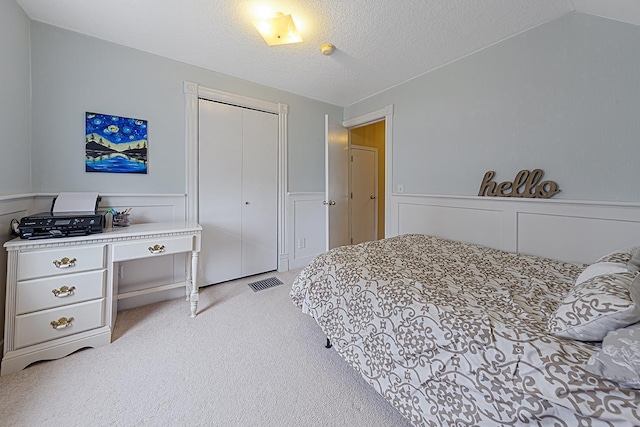 310 Belle St W, Cannon Falls, MN 55009 - bedroom with light carpet, wainscoting, a closet, and a textured ceiling