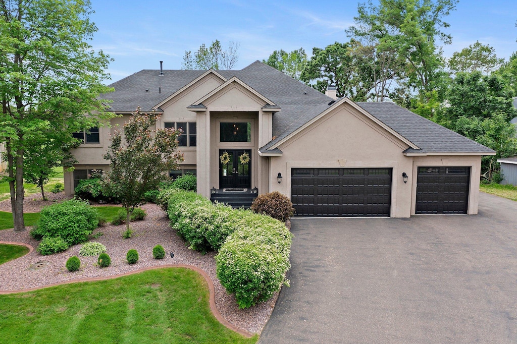 7447 213th St N, Forest Lake, MN 55025 - view of front of house featuring a garage, driveway, stucco siding, french doors, and roof with shingles