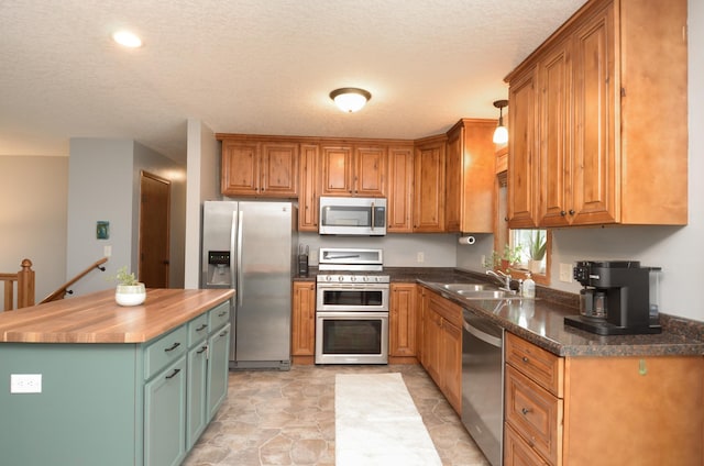 1046 Roosevelt St S, Cambridge, MN 55008 - kitchen with appliances with stainless steel finishes, wood counters, a textured ceiling, brown cabinetry, and a center island