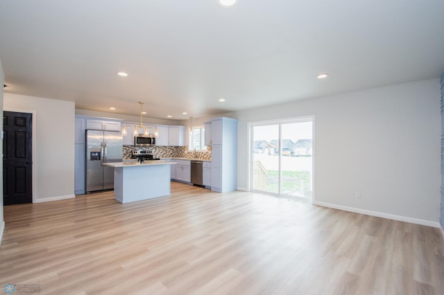 7364 27th St S, Fargo, ND 58104 - kitchen featuring appliances with stainless steel finishes, open floor plan, light countertops, backsplash, and light wood-type flooring
