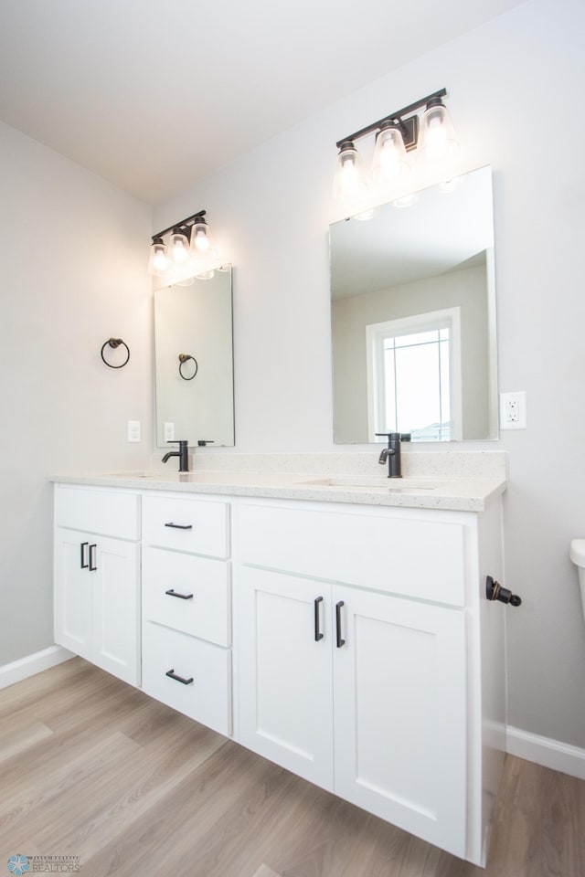 7364 27th St S, Fargo, ND 58104 - bathroom featuring double vanity, wood finished floors, baseboards, and toilet
