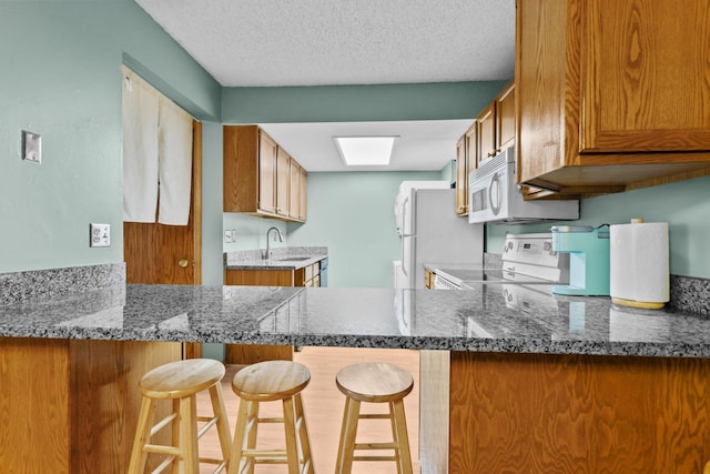 3625 Gettysburg Ave S Unit 40, Saint Louis Park, MN 55426 - kitchen featuring white appliances, a sink, brown cabinets, a peninsula, and a textured ceiling