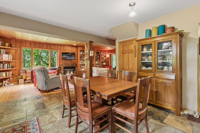 8482 150th St E, Northfield Twp, MN 55057 - dining space featuring a fireplace, stone tile flooring, and wood walls