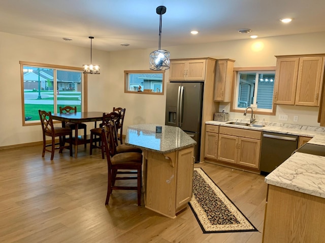 1504 3rd Ave N, Cold Spring, MN 56320 - kitchen with stainless steel appliances, light brown cabinets, light wood finished floors, a kitchen island, and a kitchen breakfast bar