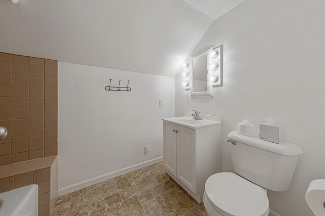 28145 State Highway 112, Le Sueur, MN 56058 - bathroom featuring vanity, vaulted ceiling, toilet, baseboards, and stone finish floors