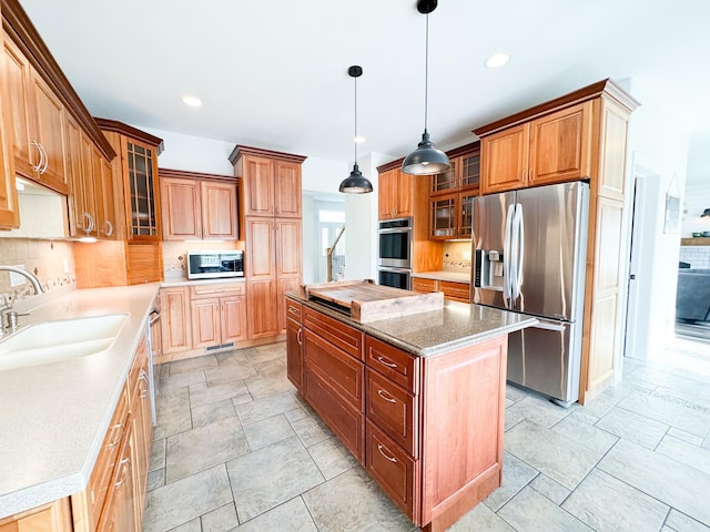 1207 Martin St, Fergus Falls, MN 56537 - kitchen featuring appliances with stainless steel finishes, a sink, a center island, decorative backsplash, and brown cabinets