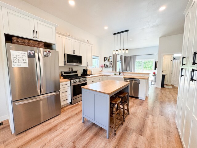 1207 Martin St, Fergus Falls, MN 56537 - kitchen featuring stainless steel appliances, a peninsula, wood counters, light wood-type flooring, and a center island