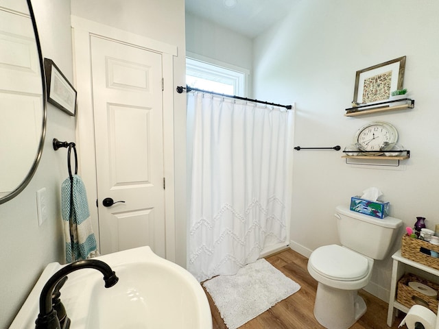 1207 Martin St, Fergus Falls, MN 56537 - bathroom featuring a sink, toilet, wood finished floors, baseboards, and curtained shower