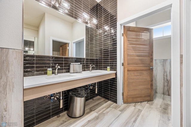 842 Rania Way W, West Fargo, ND 58078 - bathroom featuring tile walls, a sink, decorative backsplash, and wood finished floors