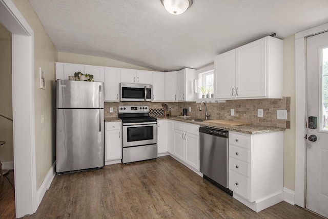 915 Cottage Ave E, Saint Paul, MN 55106 - kitchen featuring stainless steel appliances, a sink, vaulted ceiling, decorative backsplash, and white cabinets