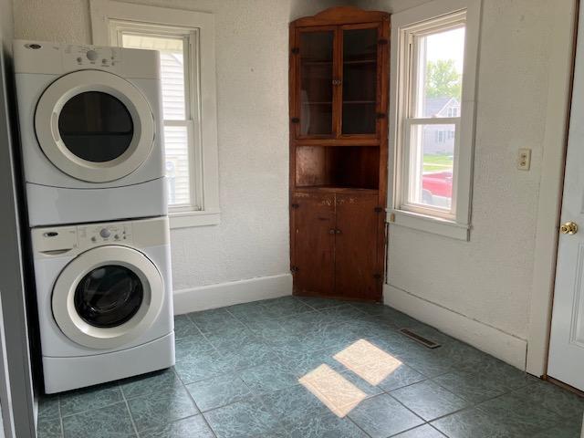 607 3rd St SW, Waseca, MN 56093 - washroom with estacked washer and dryer, healthy amount of natural light, tile patterned flooring, and baseboards