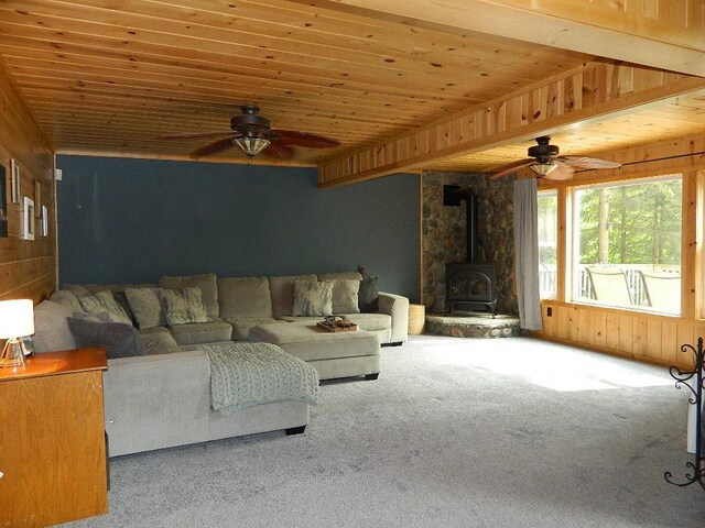3749 Grizzly Ln, Barnum Twp, MN 55707 - carpeted living area featuring a ceiling fan, a wood stove, and wooden walls