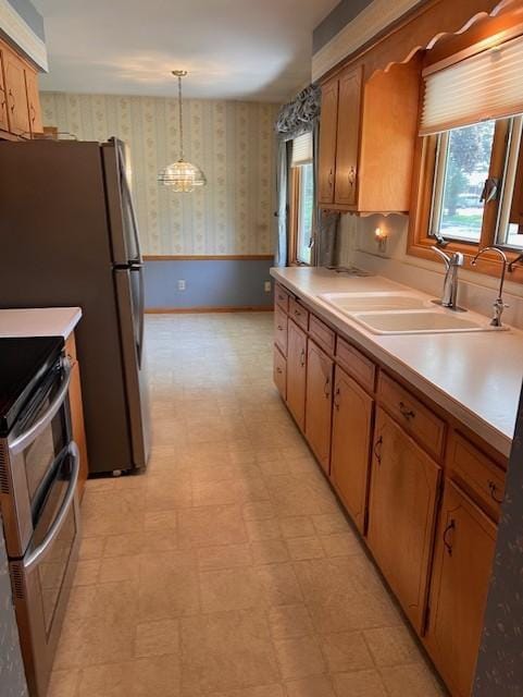 5951 Oakwood Mnr NE, Fridley, MN 55432 - kitchen with wallpapered walls, a sink, range with two ovens, light floors, and light countertops