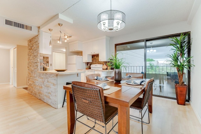 1920 1st St Unit 304, Minneapolis, MN 55454 - dining room featuring light wood-style floors, a chandelier, baseboards, and a textured ceiling