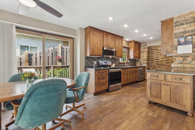 7469 Fernbrook Ln N, Maple Grove, MN 55311 - kitchen with appliances with stainless steel finishes, wood finished floors, ceiling fan, a textured ceiling, and backsplash