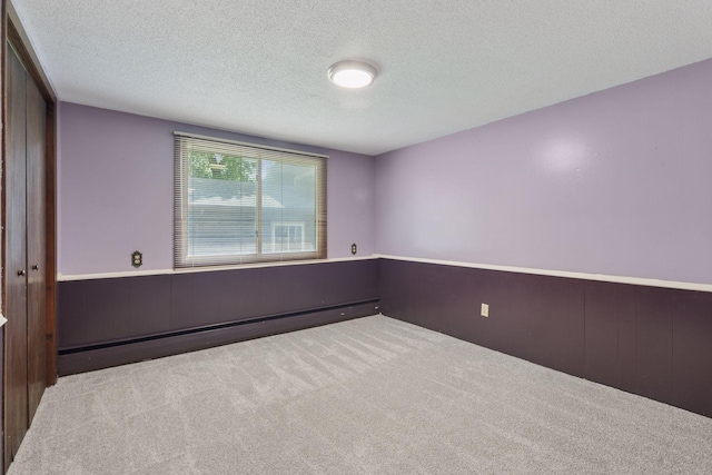 7469 Fernbrook Ln N, Maple Grove, MN 55311 - carpeted spare room featuring a baseboard radiator, a textured ceiling, and wainscoting