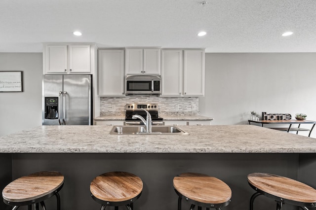 7363 146th Xing NW, Ramsey, MN 55303 - kitchen with stainless steel appliances, decorative backsplash, a kitchen bar, recessed lighting, and white cabinetry