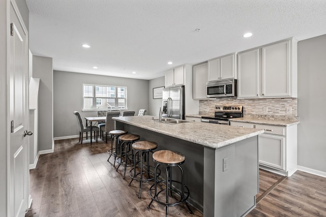 7363 146th Xing NW, Ramsey, MN 55303 - kitchen featuring stainless steel appliances, decorative backsplash, a breakfast bar area, dark wood-style floors, and recessed lighting