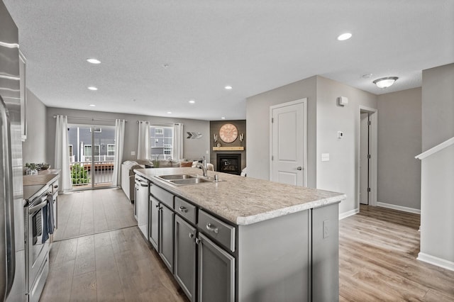 7363 146th Xing NW, Ramsey, MN 55303 - kitchen featuring a fireplace, light wood-type flooring, a center island with sink, light countertops, and recessed lighting