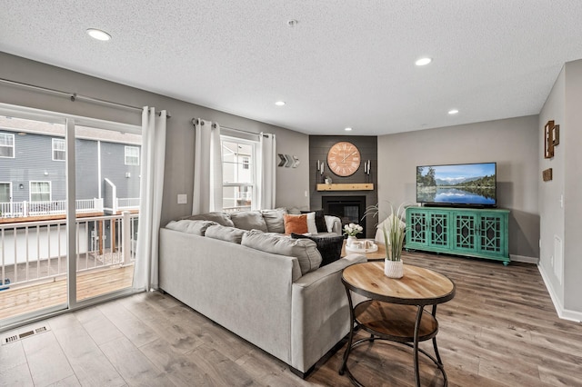 7363 146th Xing NW, Ramsey, MN 55303 - living room featuring wood finished floors, a textured ceiling, a fireplace, and recessed lighting