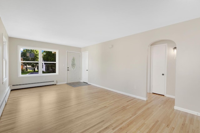 111 4th St, Kenyon, MN 55946 - unfurnished room with a baseboard heating unit, light wood finished floors, arched walkways, and baseboards