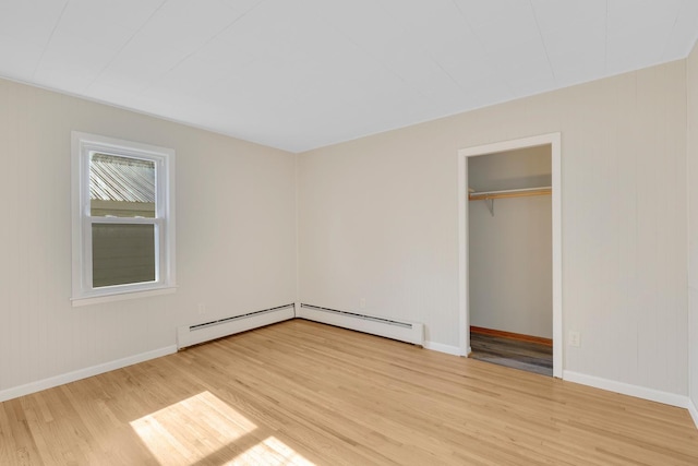 111 4th St, Kenyon, MN 55946 - unfurnished bedroom featuring wood finished floors, baseboards, and a baseboard heating unit