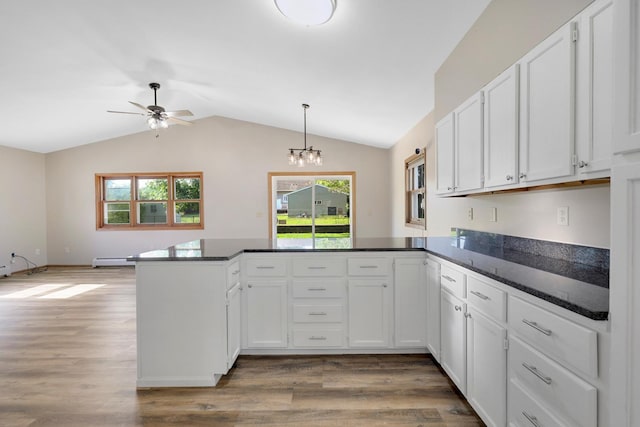 111 4th St, Kenyon, MN 55946 - kitchen with a peninsula, white cabinets, lofted ceiling, plenty of natural light, and wood finished floors