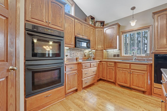 13023 Yellow Pine Cir NW, Coon Rapids, MN 55448 - kitchen featuring black appliances, a sink, decorative backsplash, light wood-style floors, and hanging light fixtures